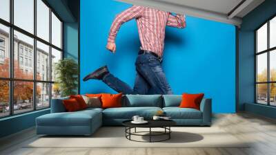 Man jumping in the air isolated on blue background Wall mural